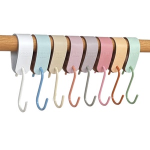 May include: A set of colorful S-shaped hooks hanging from a wooden rod. The hooks come in various pastel colors, including white, blue, beige, pink, purple, orange, and green. The hooks are designed for hanging items.
