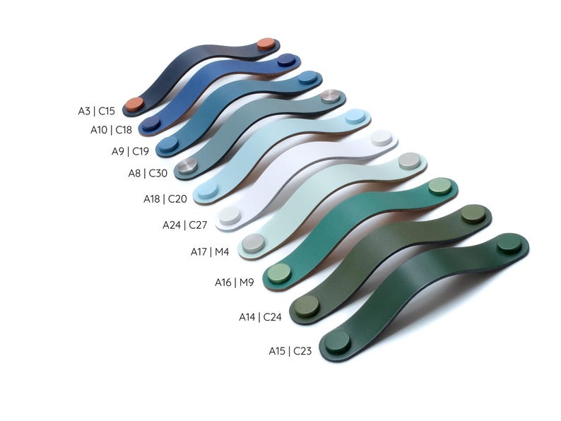 May include: A collection of ten curved cabinet handles arranged in a diagonal row, featuring various colors including dark blue, light blue, white, and shades of green. Each handle has two circular end caps with alphanumeric codes listed beside them.