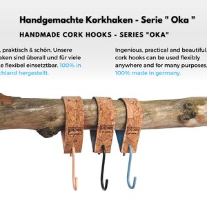 Pu&ograve; includere: Tre ganci in sughero con ganci in metallo di diversi colori. I ganci sono attaccati a un ramo e hanno la scritta "pipes" stampata su di essi. Il testo "Handgemachte Korkhaken - Serie "Oka" e "HANDMADE CORK HOOKS - SERIES "OKA" &egrave; nella parte superiore dell'immagine.