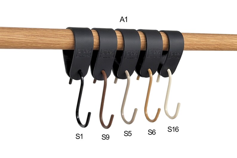 May include: A row of six black leather-like hangers with metal hooks, attached to a wooden rod. The hooks are in various colors: black, brown, beige, and off-white. The text "A1", "S1", "S9", "S5", "S6", and "S16" are visible.
