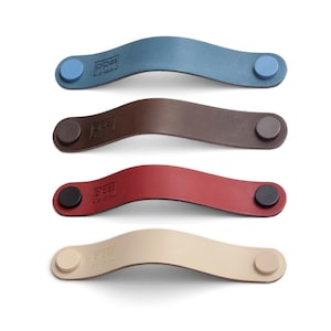 May include: Four leather drawer pulls in different colors: blue, brown, red, and beige. Each pull has a small round button on each end.