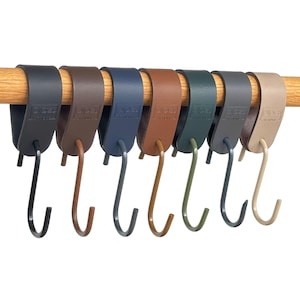 May include: A row of eight multi-colored S-hooks hanging from a wooden rod. The hooks are in shades of black, brown, blue, tan, and green. The hooks are made of metal and are designed for hanging items.