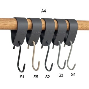 May include: A row of six dark gray S-hooks hanging from a wooden rod. The hooks are labeled S1, S2, S3, S4, and S5. The top of the hooks are attached to a dark gray band that wraps around the rod. The text "A4" is above the hooks.
