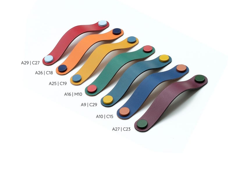 May include: Seven curved leather drawer pulls in red, orange, yellow, green, teal, blue, and purple, each secured by two contrasting circular fasteners. Text labels A29 | C27, A26 | C18, A25 | C19, A16 | M10, A9 | C29, A10 | C15, and A27 | C23 are visible.
