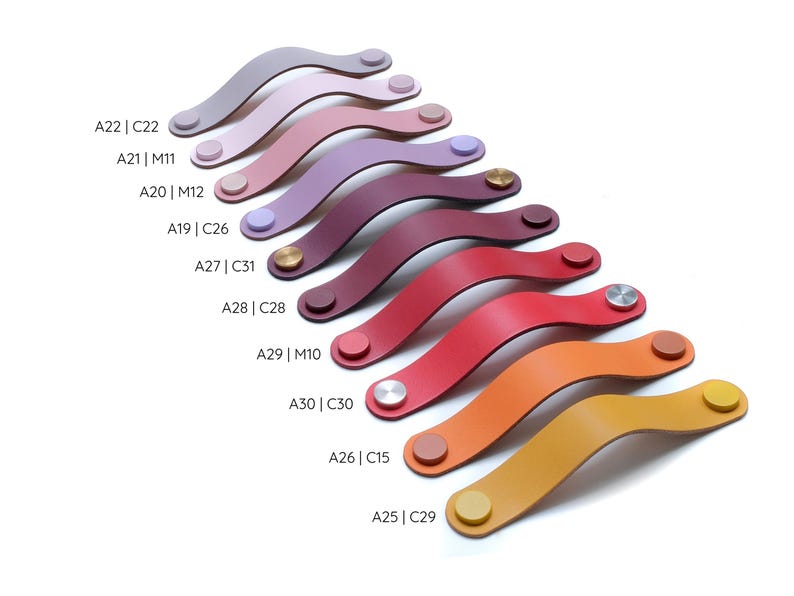 May include: A collection of curved drawer pulls in various colors including shades of purple, red, orange, and yellow. Each pull features two circular metal or matching colored fasteners. Text labels A22 | C22 through A25 | C29 are visible.
