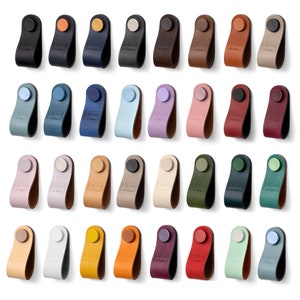 May include: Assortment of 30 leather cabinet pulls in various colors, including black, blue, brown, green, orange, pink, purple, red, white, and yellow. Each pull has a round knob and a loop for pulling.