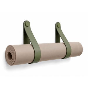 May include: A rolled beige yoga mat suspended horizontally by two olive green straps. The straps are secured to the wall with matching olive green circular fasteners, creating a simple and functional storage solution for the rolled exercise mat.