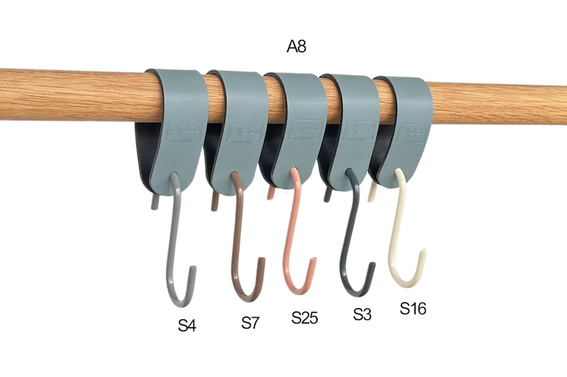 May include: A row of six gray, over-the-rod hooks with different colored hooks: gray, brown, pink, black, and cream. The hooks are hanging on a wooden rod. The text "A8" is above the hooks, and the text "S4", "S7", "S25", "S3", and "S16" are below.