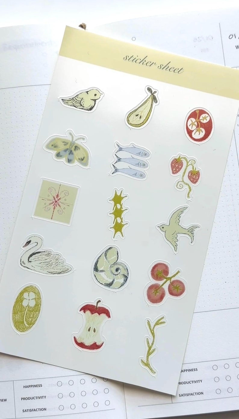 Peut inclure: Une planche d'autocollants avec diverses illustrations. Comprend un oiseau, une poire, un papillon de nuit, des poissons, des fraises, un cygne, un coquillage, un trognon de pomme et d'autres images botaniques. Le texte "sticker sheet" est imprim&eacute; en haut.