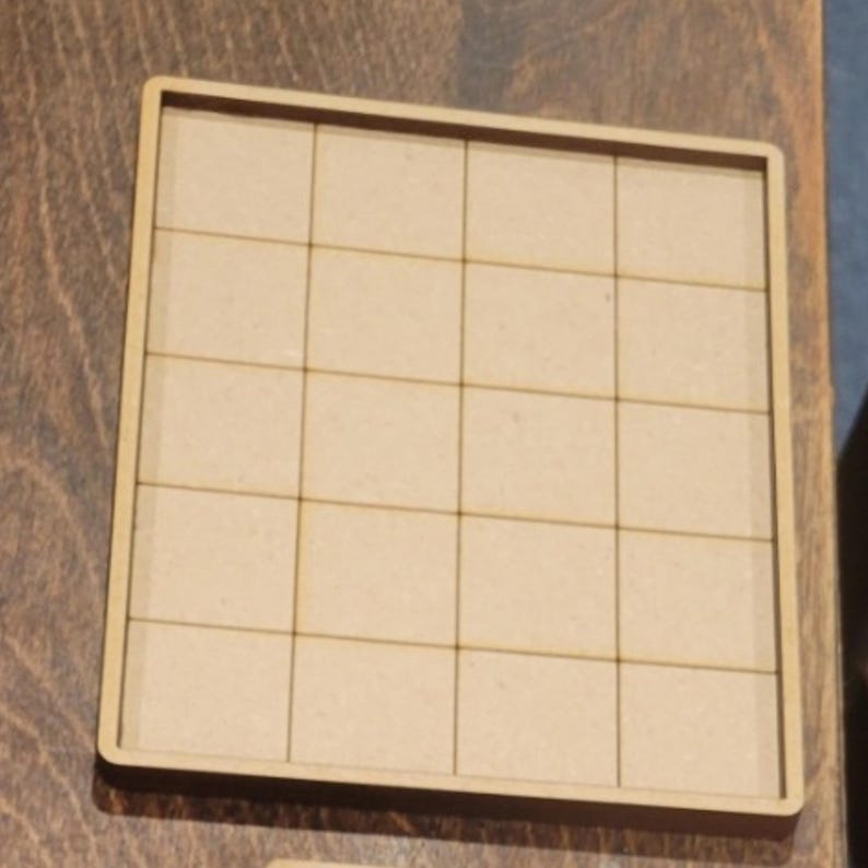 May include: A square, light-colored wooden tray with a grid pattern. The tray is divided into 25 equal squares, each approximately 1.5 inches by 1.5 inches. The edges of the tray are slightly raised, creating a border.