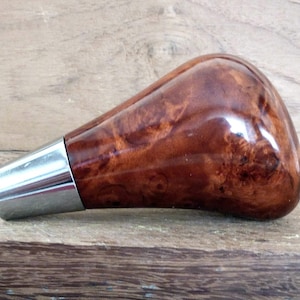 May include: A brown wood and chrome gear shift knob with a unique wood grain pattern.