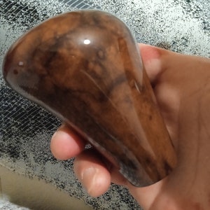 May include: A brown wooden gear shift knob with a glossy finish.