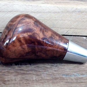 May include: A brown wood and chrome gear shift knob with a swirl pattern.