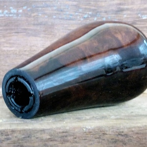 May include: A dark brown wooden gear shift knob with a black rubber grip. The knob has a smooth, polished finish.