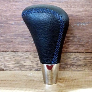 May include: Black leather gear shift knob with blue stitching and a silver base.