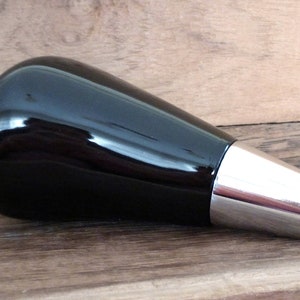 May include: Black and silver bottle stopper with a rounded, tapered shape.
