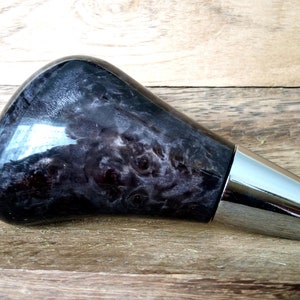 以下が含まれることがあります： クロムメッキの金属ベースが付いた黒と白の木製のシフトノブです。
