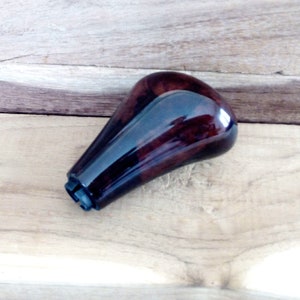 Puede incluir: Una palanca de cambios de madera marrón oscuro con una base de plástico negro.