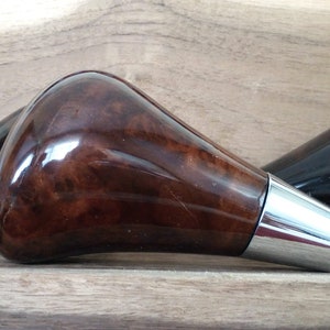 May include: Three wooden gear shift knobs with a chrome accent. The knobs are brown with a wood grain pattern and have a glossy finish.