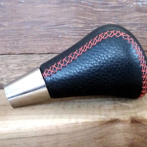 May include: Black leather gear shift knob with a silver base and red stitching.