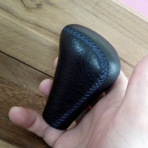 May include: Black leather gear shift knob with blue stitching.