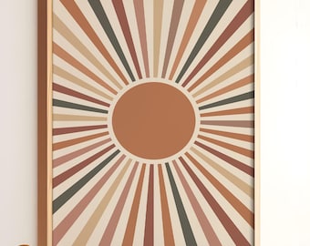 May include: A framed abstract art print with a sunburst design in shades of brown, orange, and beige. The sunburst is centered around a large, solid orange circle.