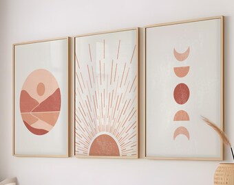 May include: Three framed prints with abstract geometric designs in shades of pink and orange. The prints feature a sun, a moon, and a landscape with a sun.