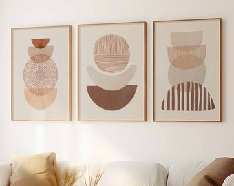 May include: Three framed abstract art prints with geometric shapes in neutral tones of beige, brown, and peach. The artwork features circles, semi-circles, and lines. The prints are displayed above a white sofa in a living room setting.