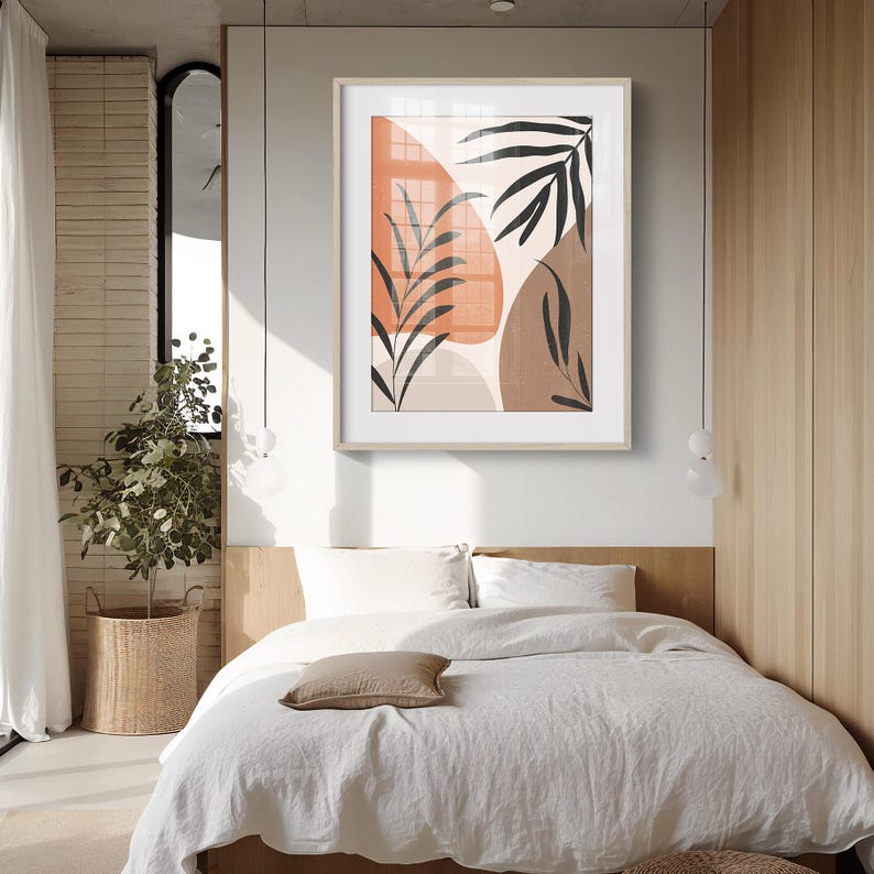 May include: A framed abstract art print with a minimalist design featuring brown, orange, and beige shapes and black leaf silhouettes.