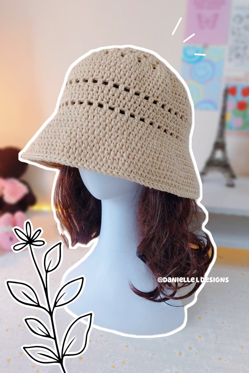 May include: A beige crochet bucket hat with a crocheted design. The hat has a wide brim and is made with a lightweight yarn.