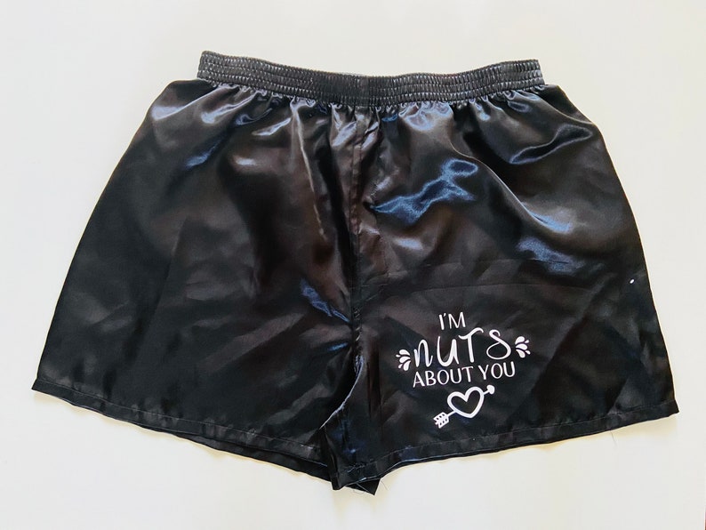 Pode incluir: Shorts de cetim preto com um gr&aacute;fico branco que diz "Estou louco por voc&ecirc;" com um cora&ccedil;&atilde;o e uma flecha.