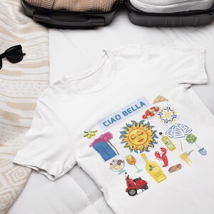 May include: White t-shirt with a colorful graphic design featuring a sun, a scooter, a window, and the text "Ciao Bella".