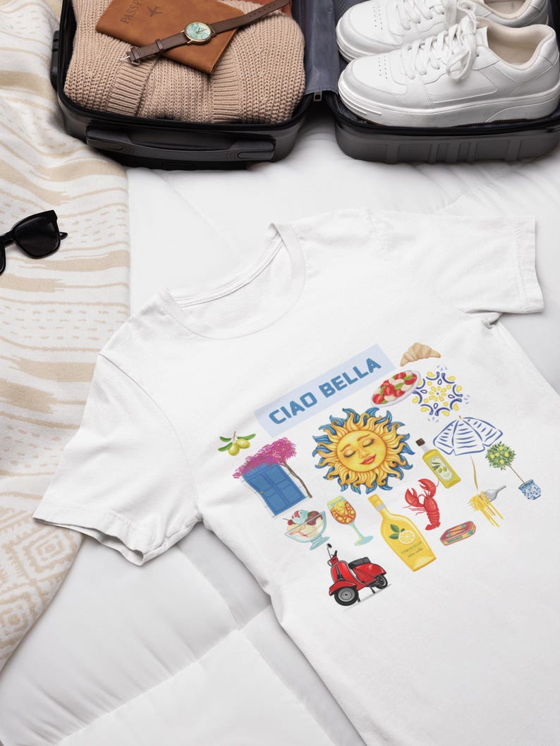 May include: White t-shirt with a colorful graphic design featuring a sun, a scooter, a window, and the text "Ciao Bella".
