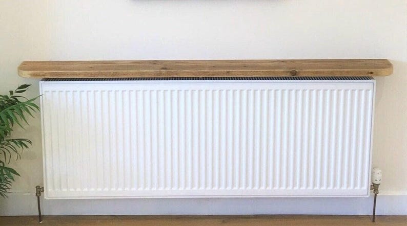 Vue de face grande tablette radiateur bois sur mesure installée sur large radiateur panneau blanc, habillage élégant et discret.
