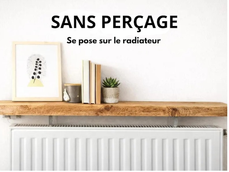 May include: A natural wood shelf mounted above a white radiator. The text SANS PER&Ccedil;AGE Se pose sur le radiateur is visible above the shelf. On the shelf are a framed print, a grey container, three books, and a small green succulent plant.