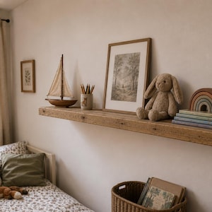 May include: A rustic wooden shelf displays a framed landscape print, a plush bunny, a wooden rainbow, and a stack of books. A toy sailboat and a pencil holder with pencils are also on the shelf. A toy fox rests on a bed with pillows.