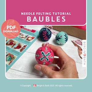May include: A pink and teal needle felted bauble with a snowflake design is held in front of a tutorial. The image includes two other baubles, one teal and one navy, and the text "NEEDLE FELTING TUTORIAL BAUBLES" and "PDF DOWNLOAD".