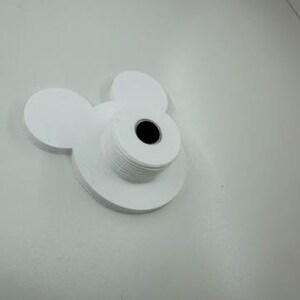 以下が含まれることがあります： ミッキーマウスの頭の形をした、白く積み重ねられたコースター。コースターは厚手の素材でできており、中央に円形のくぼみがあります。デザインは、2つの大きな耳の形をした円と、頭用の小さな円が特徴です。