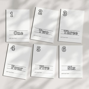 May include: Six white cards with black outlines. Each card has a number from one to six written in large, bold font. Below the number is the word for the number written in a smaller font. Each card has a line for writing "with love from".