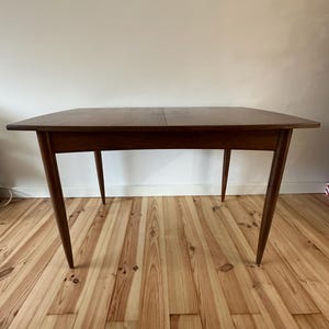 May include: A rectangular wooden table with a dark brown finish. The table has four tapered legs and a simple, minimalist design. The table is approximately 122 cm long and 76 cm wide.