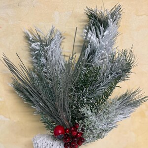 May include: A snowy pine sprig with red berries and a white pine cone. The sprig is frosted and has a green and white color scheme.