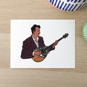 May include: A man in a purple striped suit plays a bouzouki, a traditional Greek stringed instrument. The bouzouki has a wooden body and a decorative floral design.