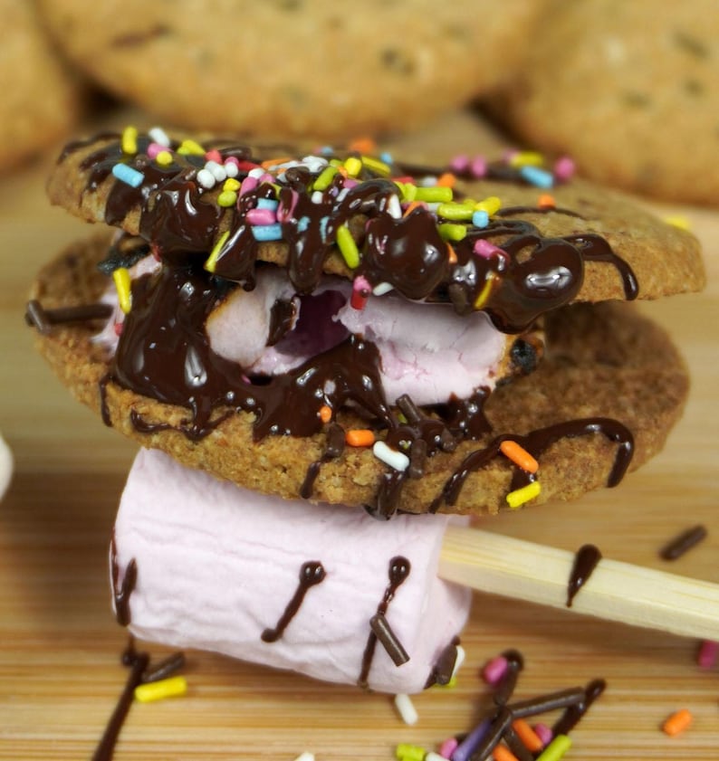 May include: A chocolate-covered s'more with pink marshmallow, two chocolate chip cookies, and colorful sprinkles.
