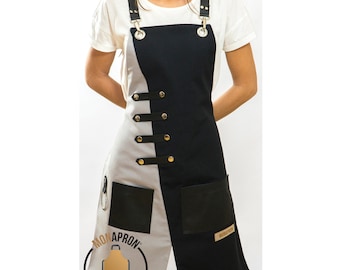 May include: Black and gray apron with adjustable straps, two pockets, and a leather patch with the text "MON APRON" and "Apron Art & Design".