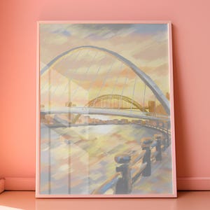 May include: A framed art print depicting a bridge over a river at sunset. The artwork shows a large, arched bridge in the foreground and a smaller bridge in the background, with a warm colour palette of yellows, oranges, and blues. The print is displayed in a pink frame.