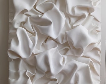 May include: A white fabric wall sculpture with a textured, wrinkled surface. The fabric is arranged in a series of folds and creases, creating a dynamic and abstract design.
