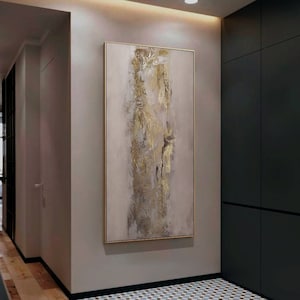 Peut inclure: Peinture abstraite aux tons dorés et beiges dans un couloir moderne. La peinture est encadrée et accrochée à un mur gris clair.