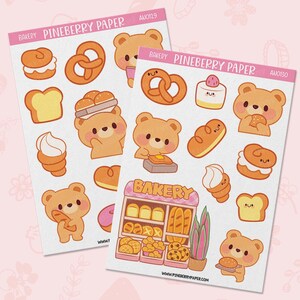 May include: Two sticker sheets labeled PINEBERRY PAPER with bakery-themed illustrations. Designs include brown bears, pretzels, bread, pastries, and a bakery storefront with the text BAKERY. The stickers feature soft orange, pink, and yellow tones.