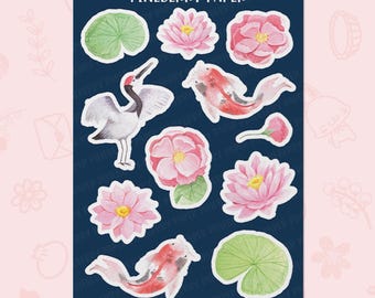 Puede incluir: Una hoja de pegatinas sobre un fondo azul oscuro con ilustraciones en acuarela de flores de loto rosas, nenúfares verdes, una grulla blanca con corona roja y dos peces koi. El texto dice LOTUS, PINEBERRY PAPER, FL0141 y WWW.PINEBERRYPAPER.COM.