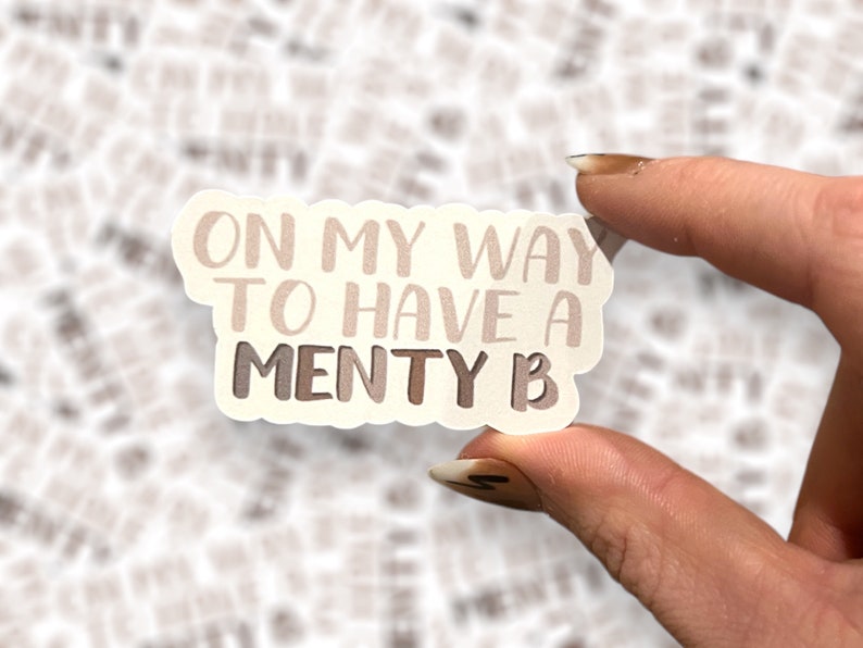 May include: A white sticker with the text "On my way to have a menty b" in brown and white lettering.